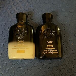 Two Oribe travel size shampoos. Both are 3/4 full or more.Gold Lust & Signature